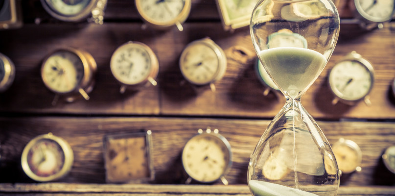 Vintage hourglass on the background of clocks
