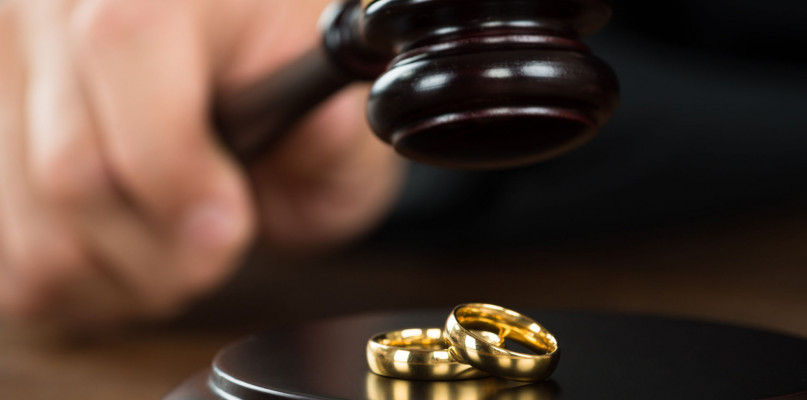 48227541 - cropped image of divorce judge hitting gavel on golden rings at desk in courtroom
